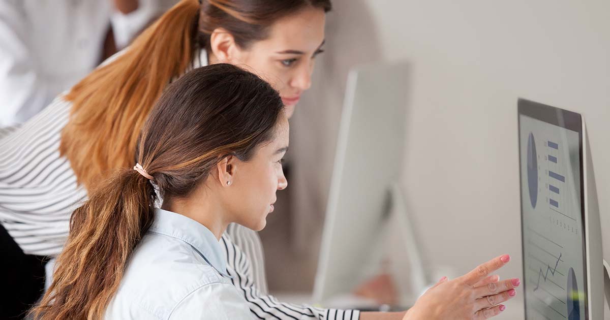 Businesswomen analyzing charts on a computer.